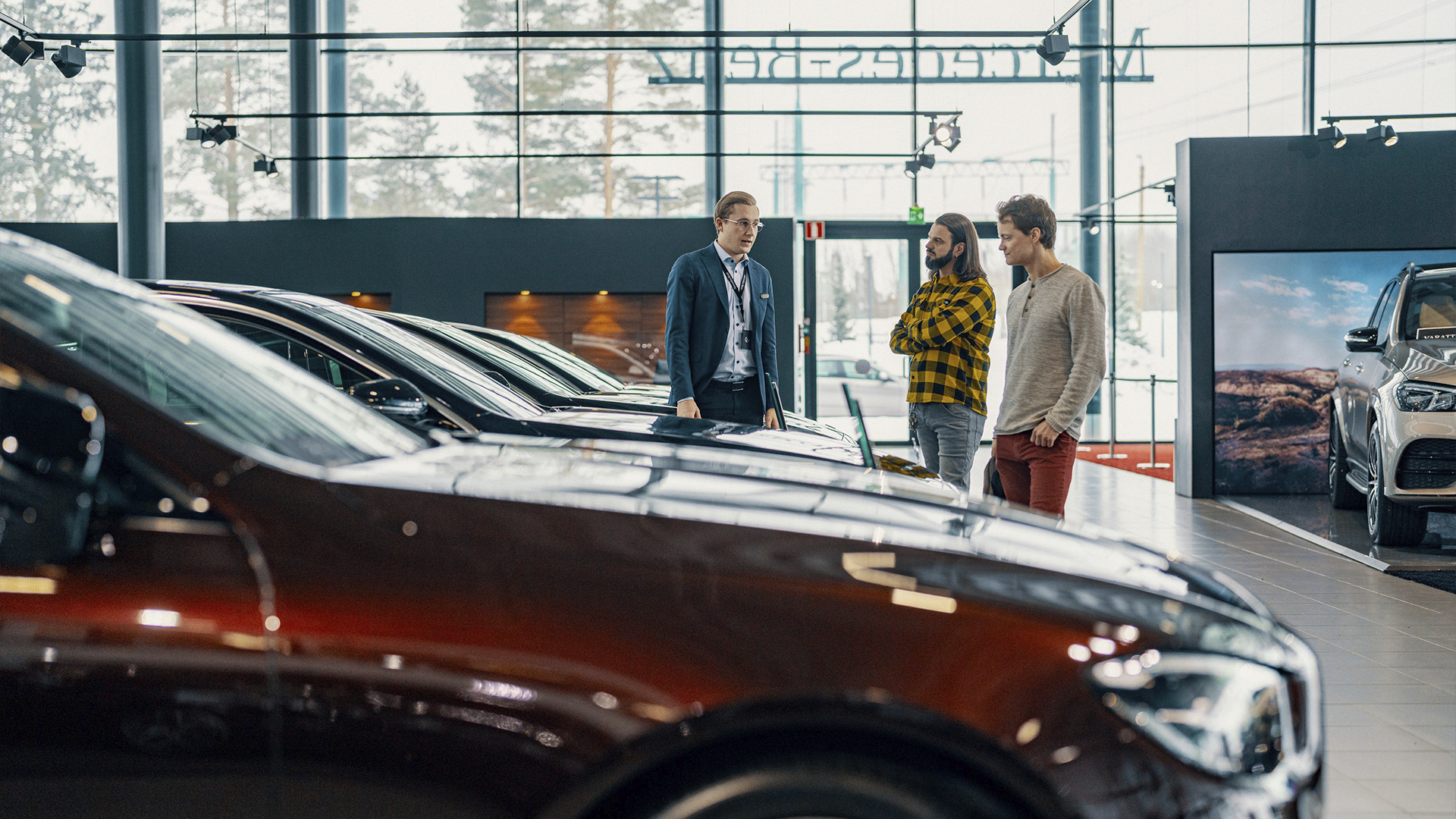Auto pārdevējs un klienti apspriež automašīnu dīlera salonā